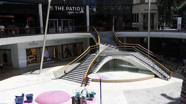 An empty Pacific Fair Shopping Centre at midday. A cleaner wipes down chairs, tables and railings. Photo: Tertius Pickard