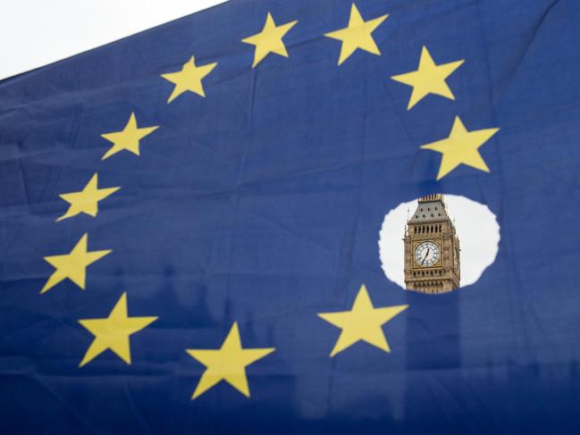 (FILES) This file photo taken on March 29, 2017 shows a pro-remain protester holds up an EU flag with one of the stars symbolically cut out in front of the Houses of Parliament shortly after British Prime Minister Theresa May announced to the House of Commons that Article 50 had been triggered in London on March 29, 2017.  EU migrants said on June 23 that far from being 