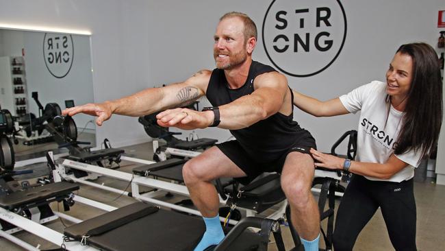 Mel Willmot puts husband Dave through his paces at their new Strong Pilates studio in Hope Island. Picture: Tertius Pickard