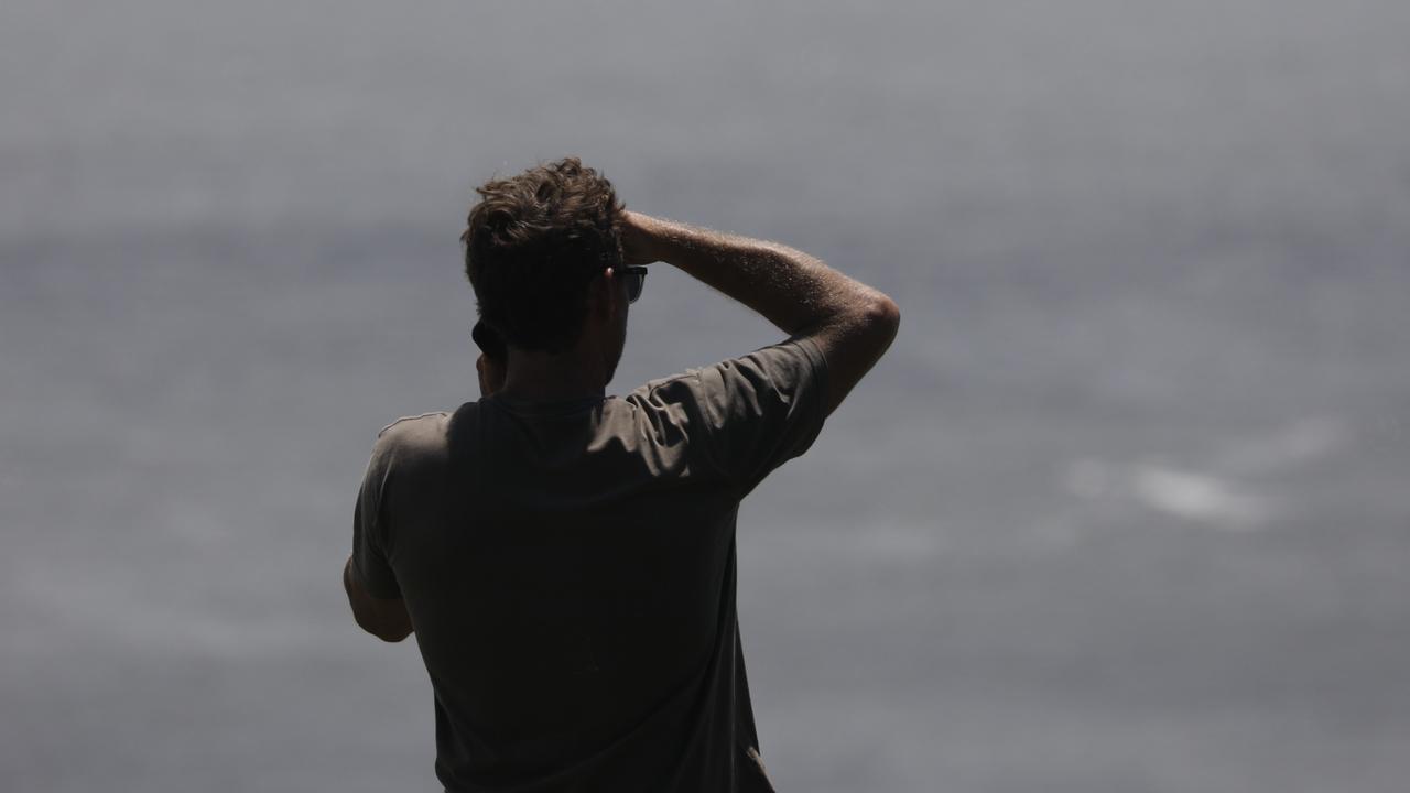 A man at Pat Morton Lookout in Lennox Head takes advantage of a rare pocket of phone reception to make a call. Picture: Liana Boss