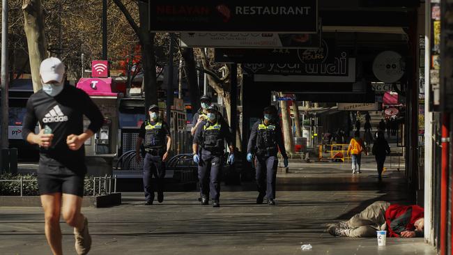 Police walk past a homeless man along Swanston Street in Melbourne. Picture: NCA NewsWire / Daniel Pockett