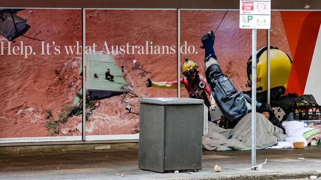 There’s a certain irony of a homeless person sleeping next to this window message on the corner of King William and Grenfell Street. Picture: Russell Millard