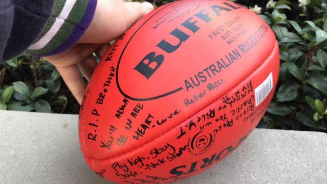 Friends sign a football in tribute to Charlie Scott.