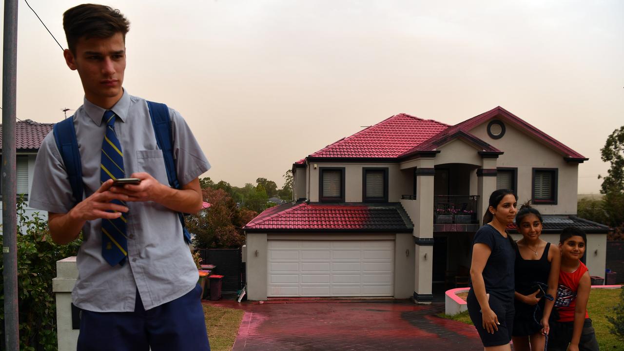 Residents pose for photographs at South Turramurra after fire retardant was dropped on homes yesterday. Picture: Getty Images