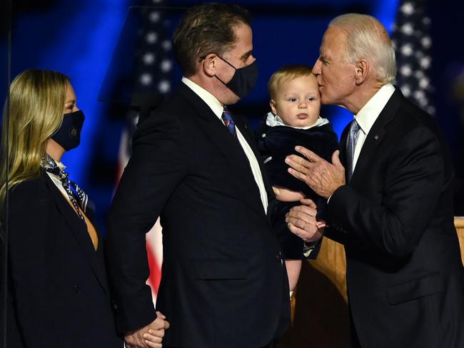 Joe Biden, far right, kisses his grandson held by son Hunter Biden. Picture: AFP