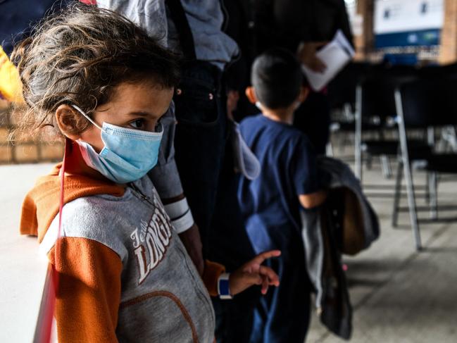 A migrant girl from Central America waits with her mother for a bus after they are dropped off by the US Customs and Border Protection. Picture: AFP