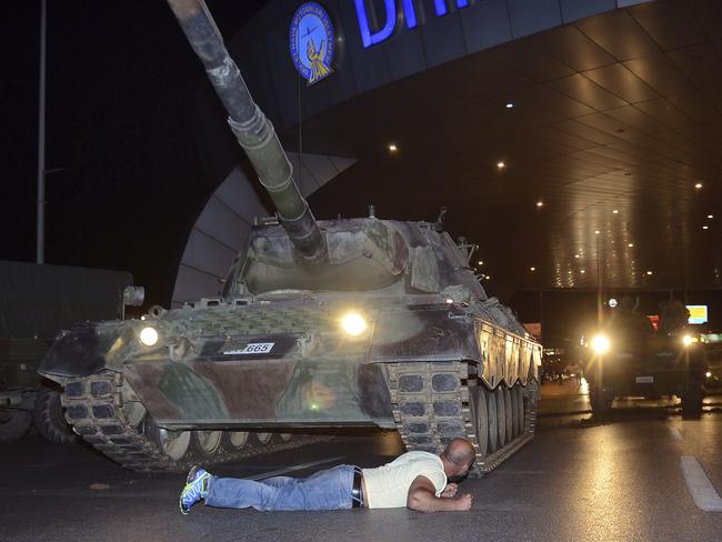 A man lays in front of a tank in the entrance to Istanbul's Ataturk airport, early Saturday morning. Picture: Ismail Coskun/IHA via AP