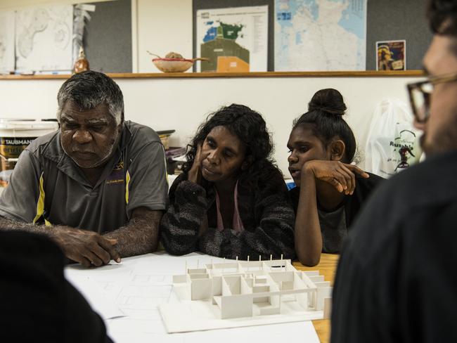 Tennant Creek resident Norm Frank Jupururrla, his wife Serena Morton Nabanunga and daughter look at a cardboard model of a preliminary house designed for the Wilya Junta (Standing Strong) Housing Collaboration. Picture: Supplied/Andrew Quilty.