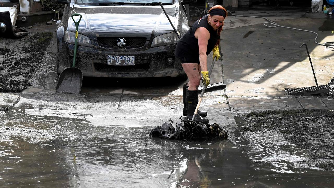 A woman sweeps mud from a property affected by the Maribyrnong floods. Picture: William West/AFP.