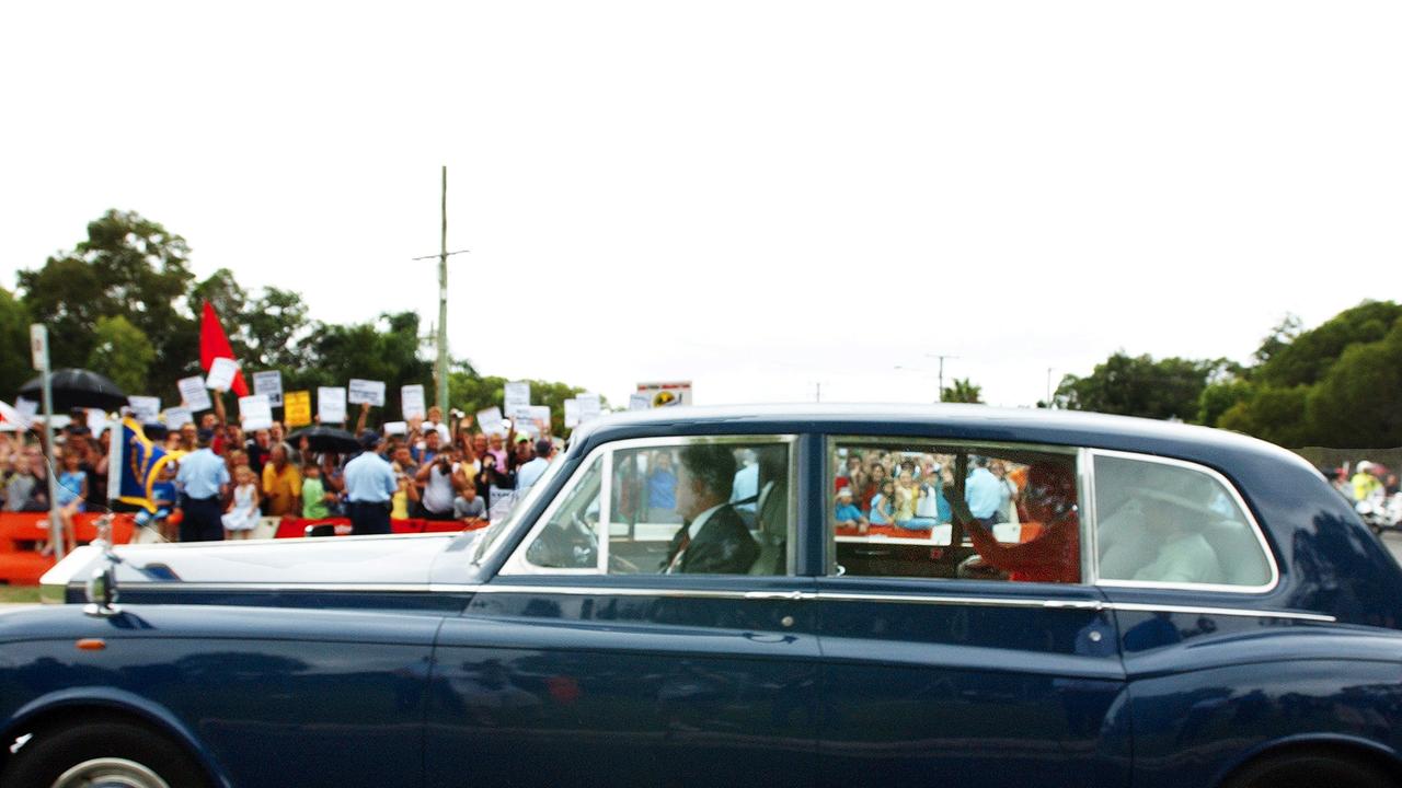 Her Majesty Queen Elizabeth 11 is escorted to the Commonwealth Heads of Government Meeting in 2002, passing protesters along the way (AAP Image/Dave Hunt)