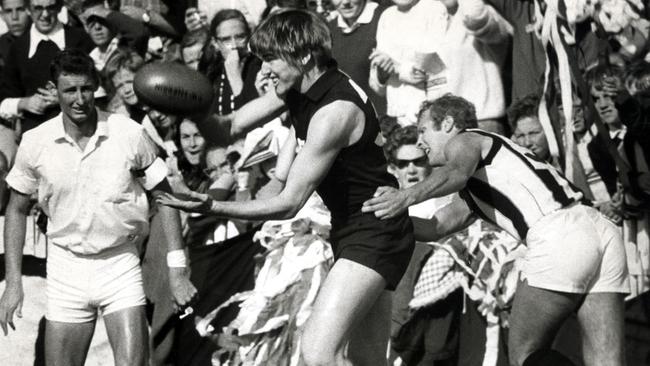 Bryan Quirk gets a handball away as he is grabbed by Collingwood’s Terry Waters in 1969