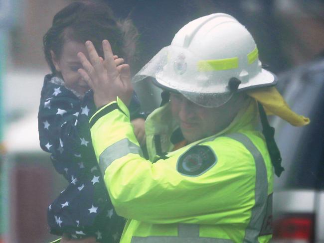 An RFS volunteer carries a child after evacuations in North Narrabeen / Picture: John Grainger