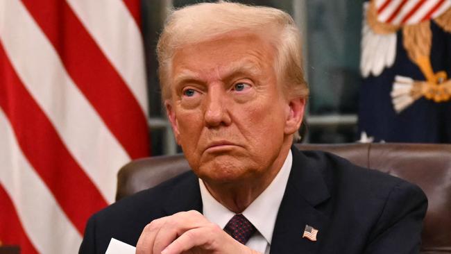 US President Donald Trump holds up outgoing President Joe Biden's letter as he signs executive orders in the Oval Office of the WHite House in Washington, DC, on January 20, 2025. (Photo by Jim WATSON / POOL / AFP) / ALTERNATE CROP