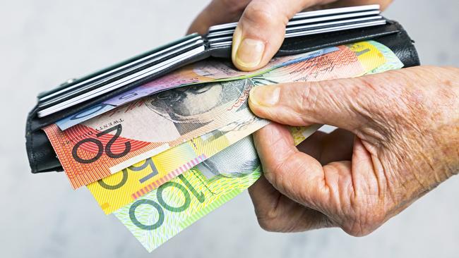 Close-up, senior female hands taking Australian banknotes (cash, currency) from purse containing many credit cards.  Horizontal, studio, copy space. Money generic