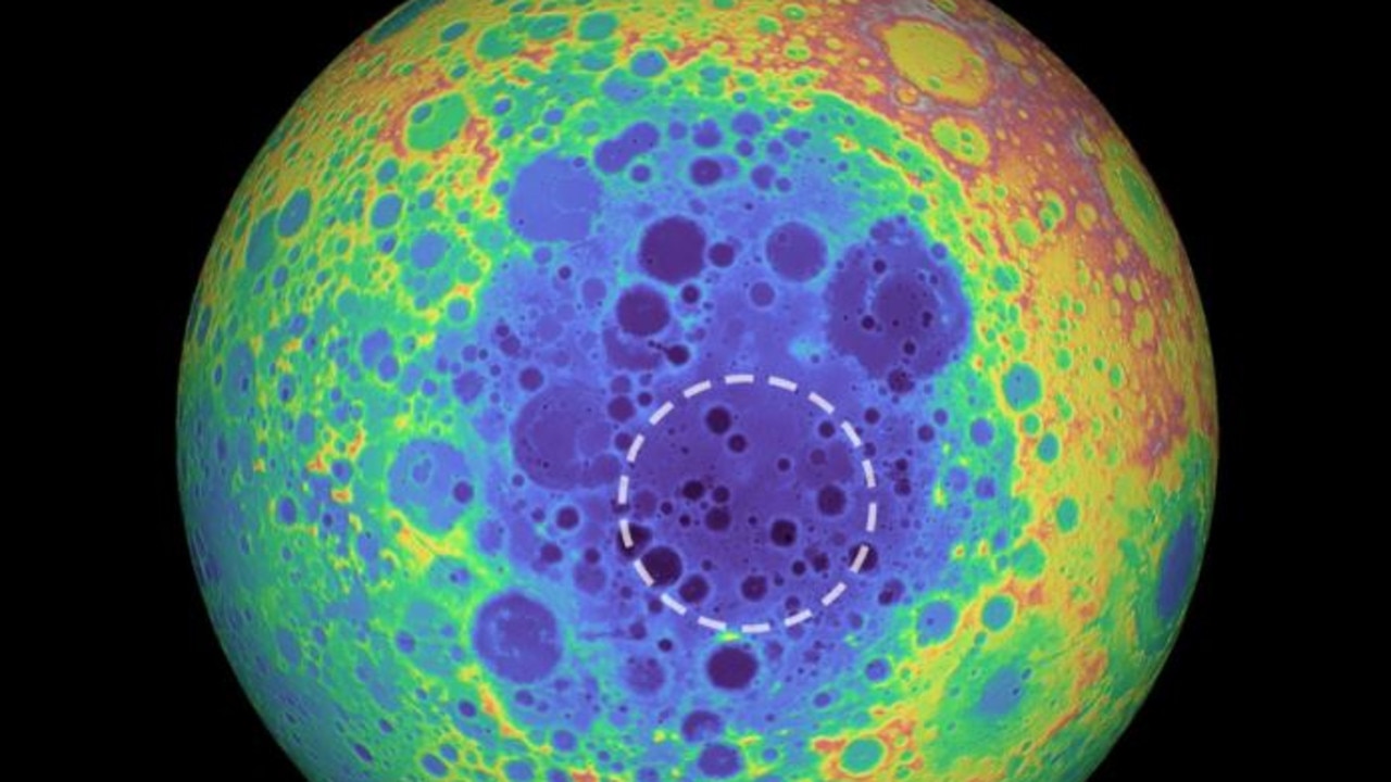 This false-colour graphic shows the topography of the far side of the Moon. The warmer colours indicate high topography and the bluer colours indicate low topography. The South Pole-Aitken (SPA) basin is shown by the shades of blue. The dashed circle shows the location of the mass anomaly under the basin. Picture: NASA/Goddard Space Flight Center/University of Arizona