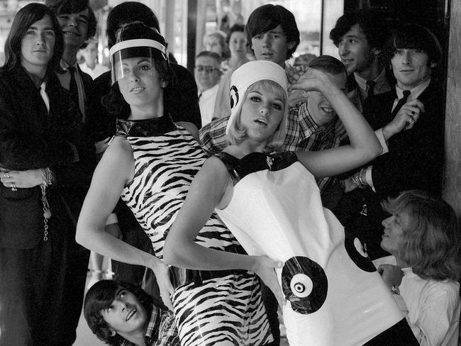 News/fashion 4/4/1966 The new, slicker go-gear for the 15-20 year-old group won appreciative applause from a band of way-out boys when it was previewed in Queen Street, Brisbane by models Mignon Haslar, left, 22, of NZ, and Desley Eldridge, 17, of Mt Gravatt. Mignon's mini dress was in black belted mock tiger vinyl and Desley chose an on-target shift in shiny black and white plastic. Picture by Ray Saunders RS322-9 pub 5/4/66 The Courier-Mail Photo Archive.