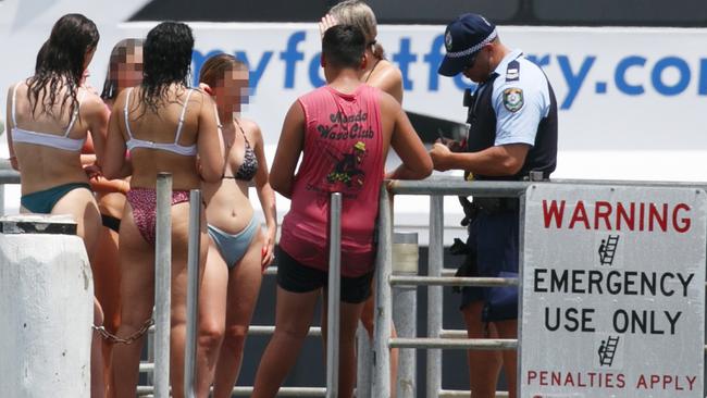 Police take down the names of young swimmers jumping from Manly Wharf on Thursday after ferry captains warned that people leaping into the harbour could be badly hurt by vessels. Picture: Tim Pascoe