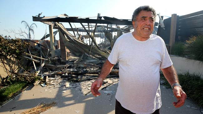 Disbelief ... resident Jimmy Eiuera inspects his friend’s destroyed home. Pictures: Ray Strange