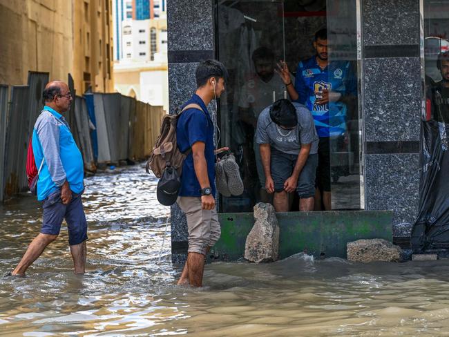 People wade through a flooded street following heavy rains in Sharjah. Picture: AFP