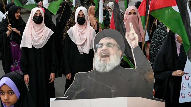 Shiite Muslims carrying Palestinian national flags stand beside a portrait of slain Lebanese Hezbollah chief Hassan Nasrallah, during an anti-Israel protest in Lahore. Picture: AFP