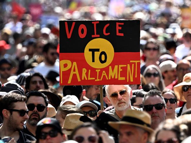 (FILES) Crowds hold up a placard of the Australian Aboriginal Flag during a "Walk for Yes" rally for the upcoming "Voice" referendum in Melbourne on September 17, 2023. A referendum aimed at elevating the rights of Indigenous Australians has instead triggered a torrent of racist slurs and abuse, with toxic debate spreading online and in the media. The October 14 vote will decide whether to finally recognise First Nation peoples in the constitution as Australia's first inhabitants. (Photo by William WEST / AFP)