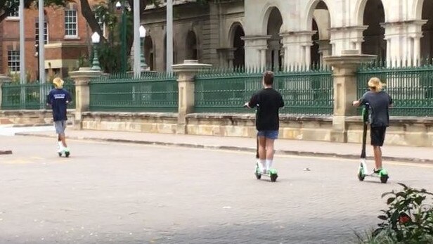 Three students motor past Queensland parliament on Friday. Not only did they appear below the minimum 16-year-old riding age, they were not wearing helmets and they rode into the ‘no go’ zone at QUT Gardens Point Campus. Picture: Darren Cartwright