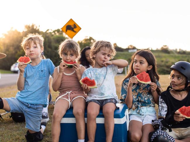 Aussie and mums and their kids eat watermelon under a koala sign