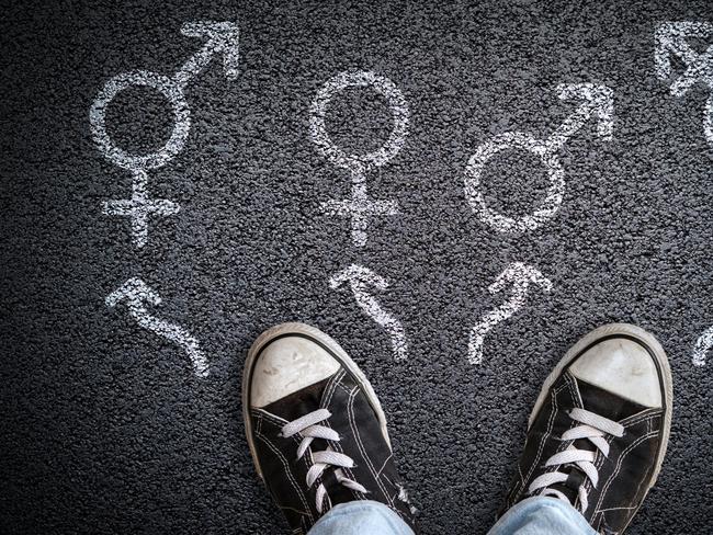 A person standing on asphalt road with gender symbols of male, female, bigender and transgender.  Concept of choice or gender confusion or dysphoria. Istock