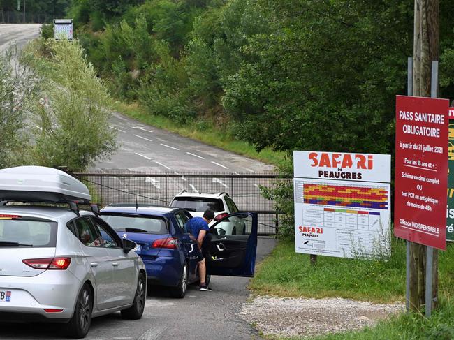 People wait in their cars next to sign that reads as "obligatory Covid-19 health passport" at the entrance of a safari park in central France. Picture: AFP