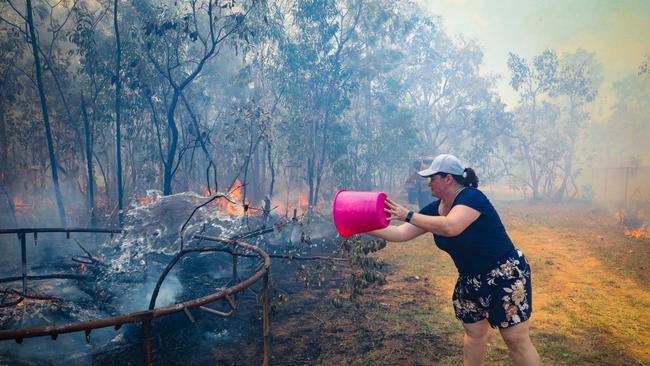 Suzanne Pilke defends her property during a bushfire at Richardson Rd, Humpty Doo. Picture: Glenn Campbell