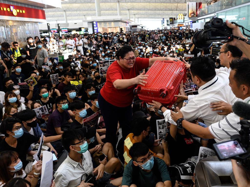 A tourist gives her luggage to security guards as she tries to enter the departures gate during another demonstration by pro-democracy protesters at Hong Kong's international airport. Picture: Philip Fong/AFP