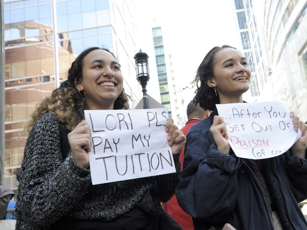 Mackenzie Thomas and Vivi Bonomie hold signs mocking Lori Loughlin outside the courthouse. 