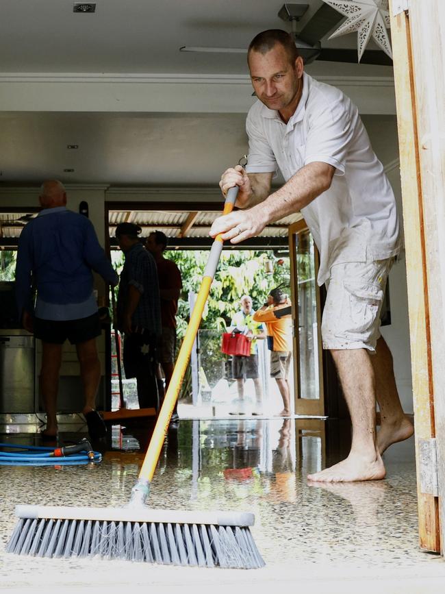 Garry Henry sweeps water out of a house at a Lake Placid Road home on Monday. Major flooding has affected low lying areas of Cairns in Far North Queensland on Sunday night. Picture: Brendan Radke