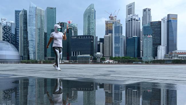 A woman, wearing a face mask walks along the promenade at Marina Bay in Singapore at the height of the pandemic. Picture: AFP.