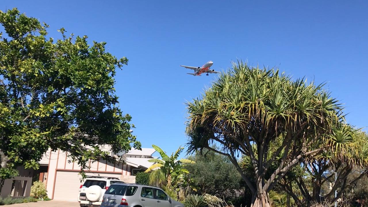 An aircraft flies over houses at Mudjimba on approach to Sunshine Coast Airport.