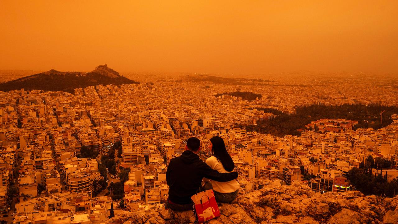 A couple sits atop Tourkovounia Hill in Athens, overlooking a haze of Saharan dust carried by southerly winds. This severe dust storm - one of the worst since 2018 - has blanketed the city, reducing visibility and prompting health warnings. Picture: Angelos Tzortzinis/AFP