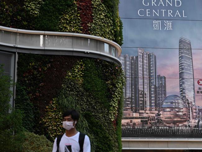 A man walks past a billboard for the Grand Central residential building complex in Hong Kong where a one-bedroom apartment has been offered for in a lucky draw for locals to get vaccinated. Picture: AFP