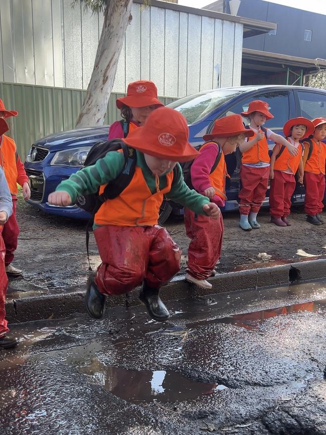 Children at John Brotchie Daycare jump in puddles. Picture: Emily Kowal,