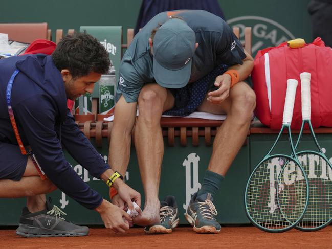 Australia's Alex De Minaur gets medical assistance for a foot injury. Picture: AP Photo