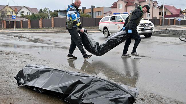 Communal workers carry body bags to a waiting van. Picture: Sergei SUPINSKY / AFP