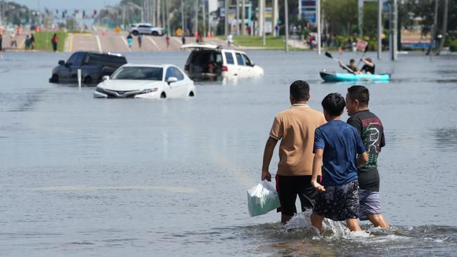 Kids walk past vehicles flooded in the water as the streets of the Southeast Seminole Heights section of Tampa due to Hurricane Milton on October 10, 2024 in Florida. Hurricane Milton tore a coast-to-coast path of destruction across the US state of Florida, whipping up a spate of deadly tornadoes that left at least four people dead, but avoiding the catastrophic devastation officials had feared. (Photo by Bryan R. SMITH / AFP)