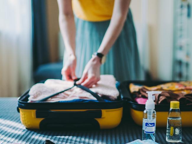 Woman packing suitcase for summer trip, including face masks and travel-sized antibacterial hand gelsA few items this doctor will never travel without