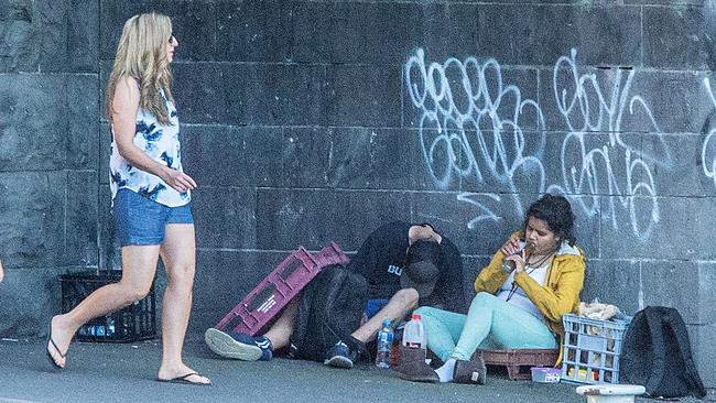 People smoke a bong alongside the Yarra River underneath Riverland Bar as Australian Open Tennis patrons walk past. Picture: Mark Stewart