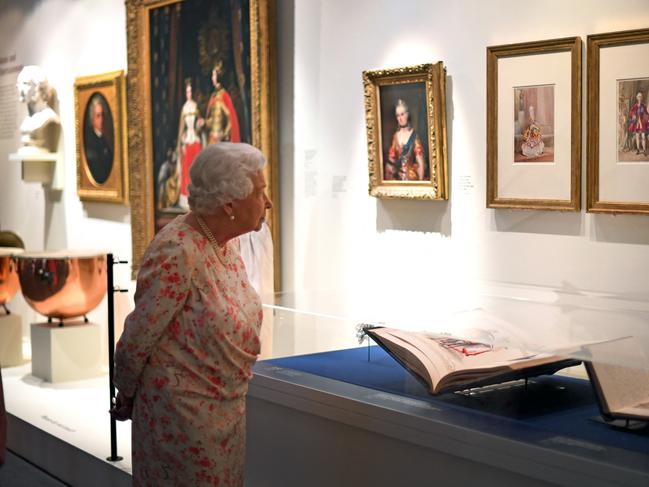 Queen Elizabeth II looks at portraits of Queen Victoria and Prince Albert by Louis Haghe. She had a wealthy portfolio of art. Picture: AFP