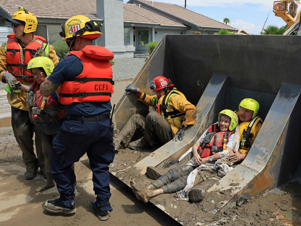 Mission complete. Cathedral City Fire Department rescuers help residents off a bulldozer. Picture: AFP