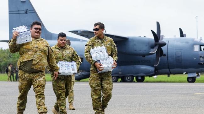 Australian Army personnel carry supplies off a cargo plane at Cooktown Airport. The entire community of Wujal Wujal has been evacuated following the flood emergency, with the majority of the town staying at the Cooktown PCYC, which is set up as an evacuation centre by the Australian Red Cross. Picture: Brendan Radke