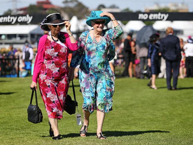 Young and old have to hold on to their hats as the wind sweeps across Flemington. Picture: Mark Stewart