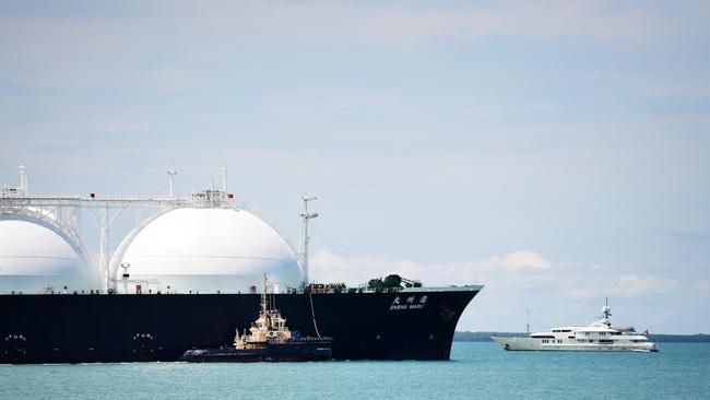 A cargo ship with natural gas dwarfs a yacht in Darwin Harbour as it departs from the Ichthys LNG Project. Picture: Justin Kennedy