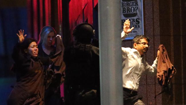 Hostages flee the Lindt Cafe into the arms of waiting tactical officers. The inquest today heard the head negotiator was juggling four other high-risk stand-offs at the same time. Picture: AAP