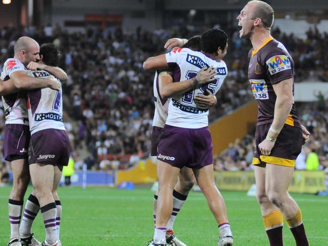 Broncos skipper Darren Lockyer reacts as Storm players celebrate their win.